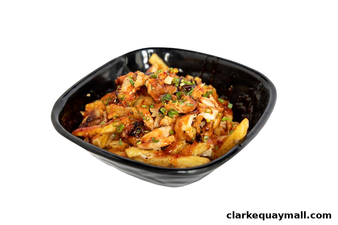A black bowl filled with crispy fries topped with chopped chicken and a savory sauce.