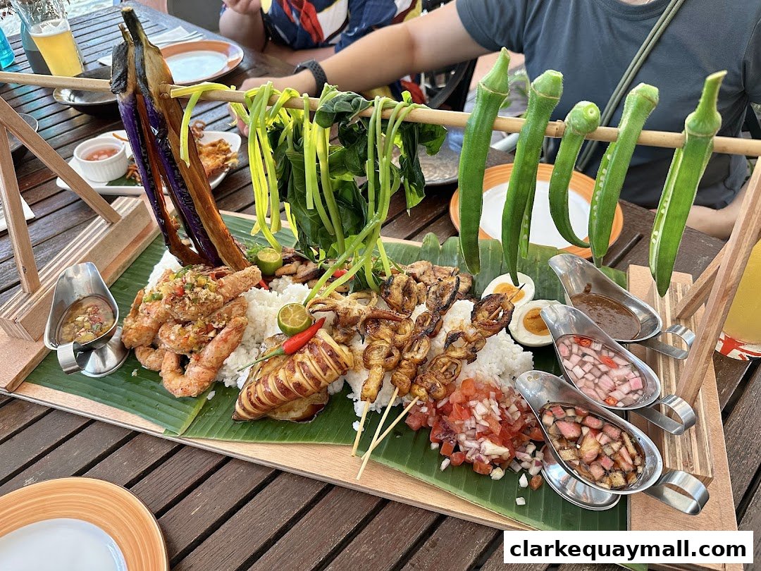 A platter of Filipino seafood and grilled items served with rice and dipping sauces.