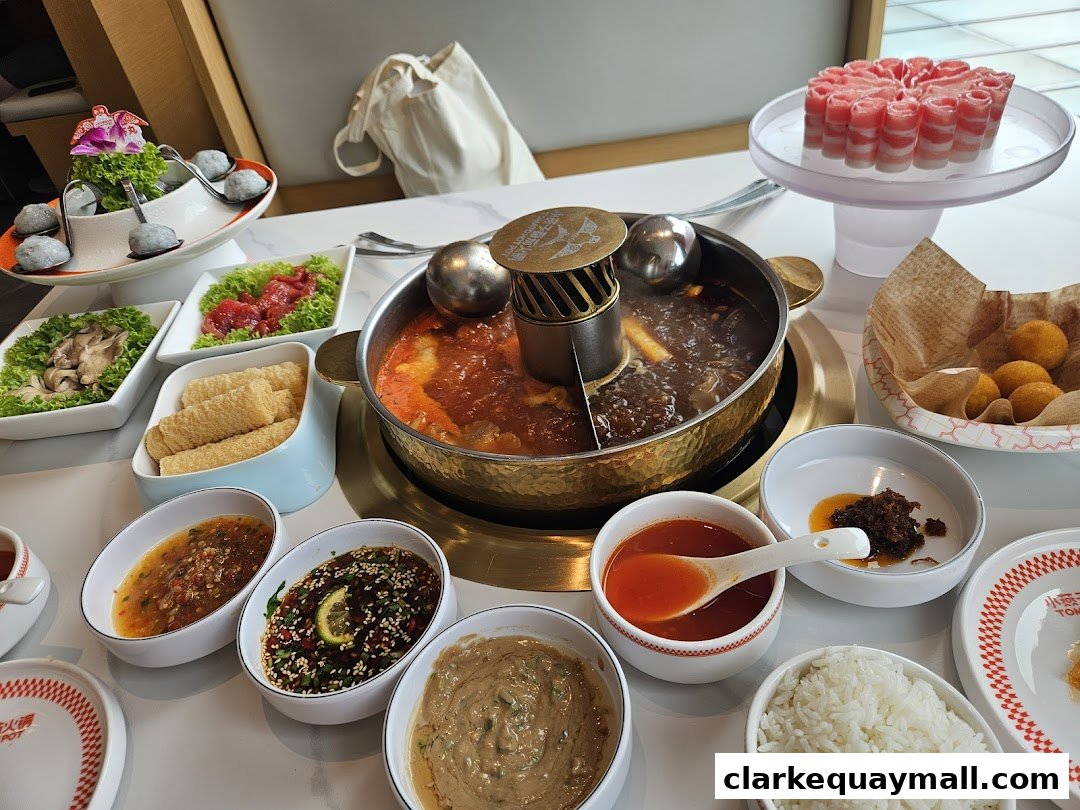 A table laden with a variety of hot pot ingredients, dipping sauces, and rice.