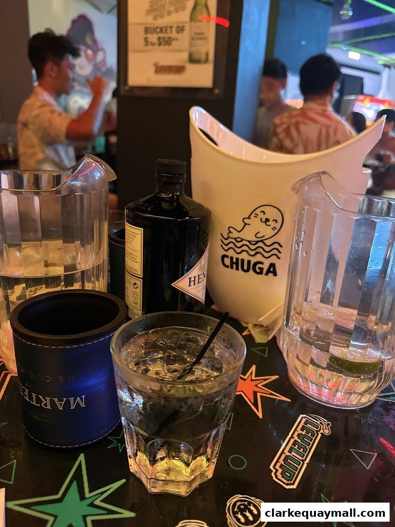 Drinks and ice buckets on a table at a lively arcade bar.