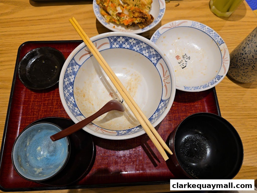 A close-up of a table with used bowls, chopsticks, and a spoon after a meal.