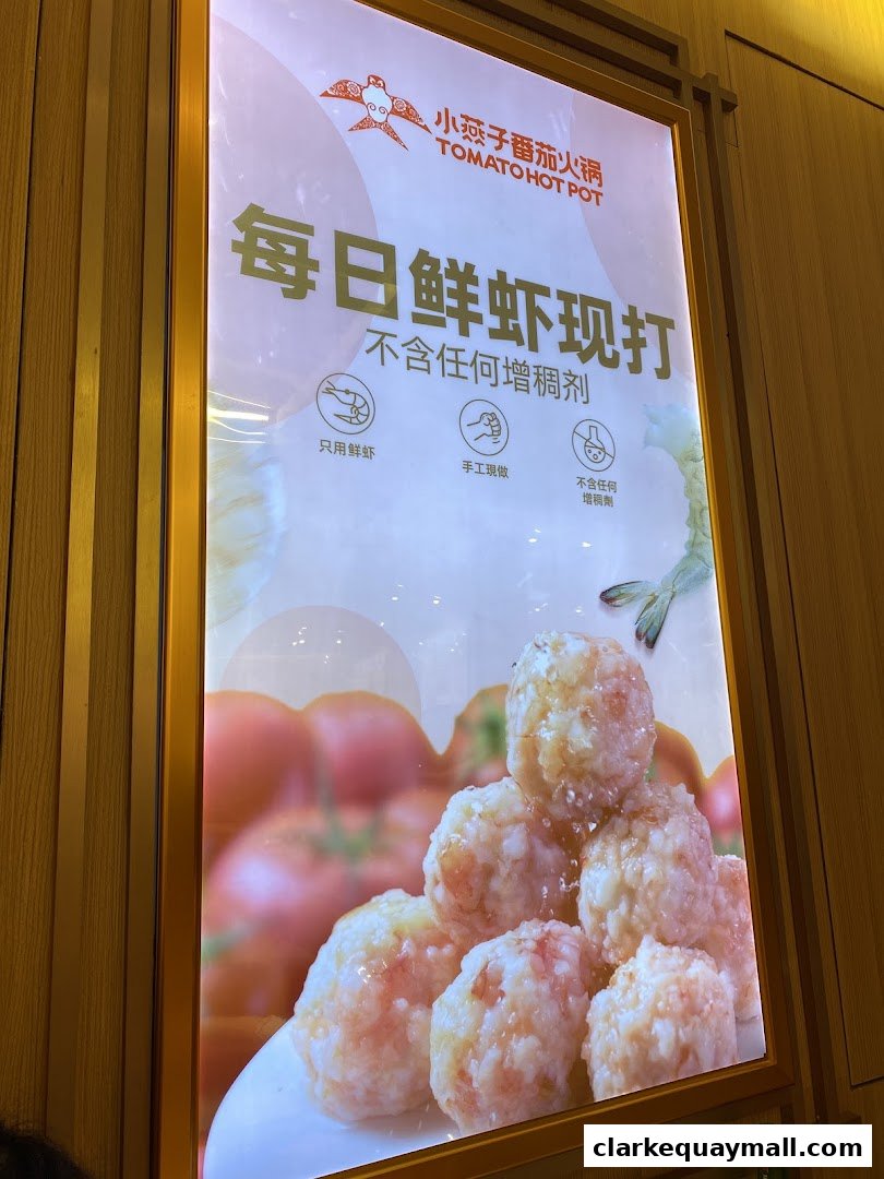 A glowing advertisement for XiaoYanZi Tomato Hot Pot featuring fresh shrimp balls.