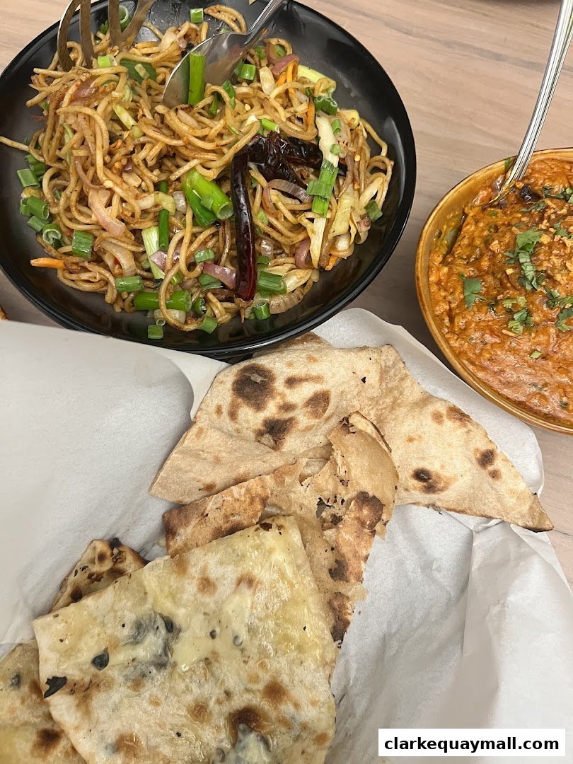 A close-up shot of delicious Indian food, featuring noodles, curry, and naan bread.