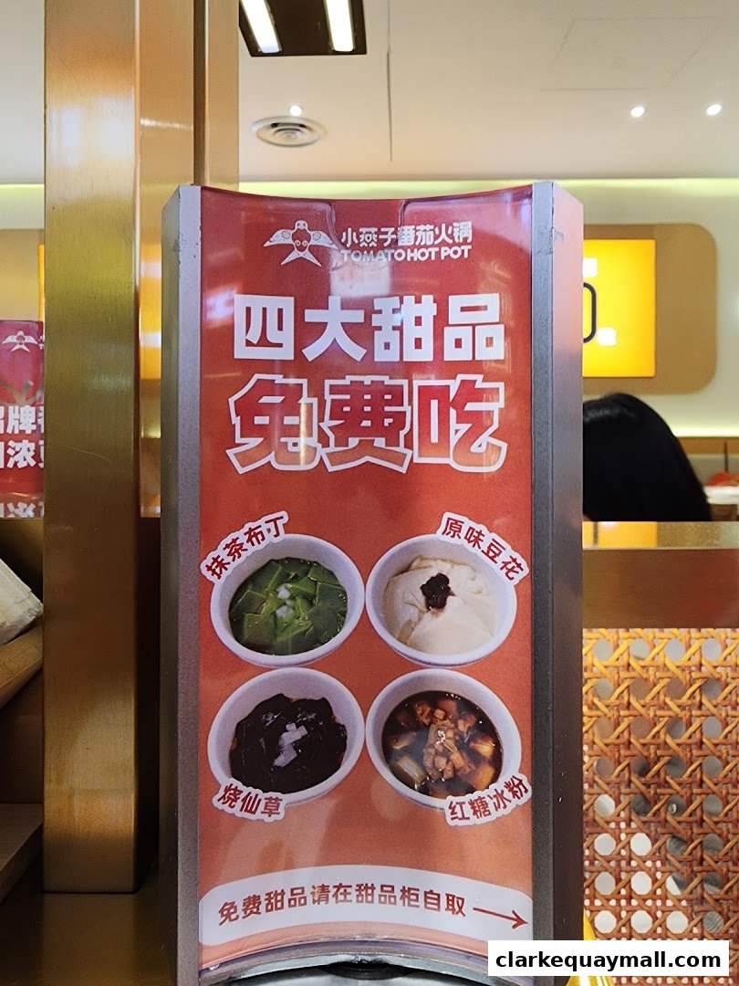 A sign advertising four free desserts from Tomato Hot Pot, featuring various sweet treats.