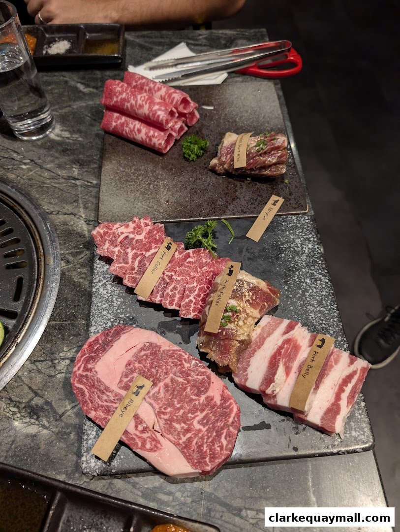 Assortment of premium raw meats, including ribeye and pork belly, ready for grilling.