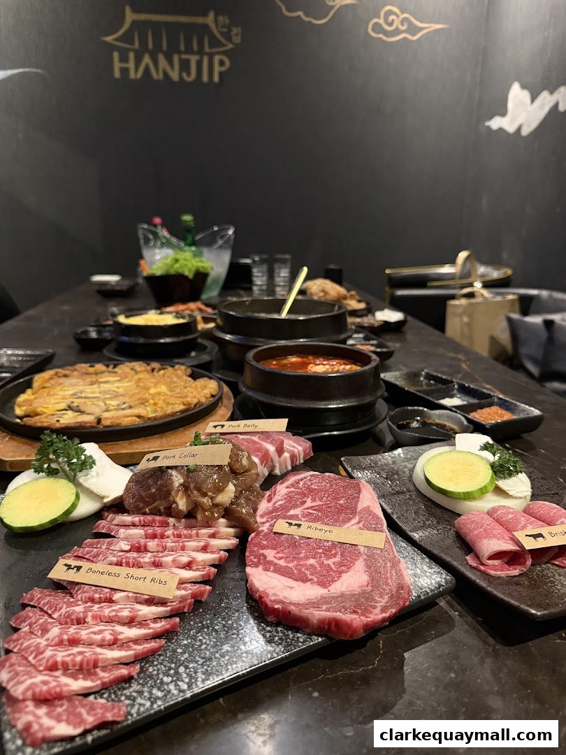 A table laden with various cuts of raw meat, Korean dishes, and drinks at Hanjip Korean Grill House.