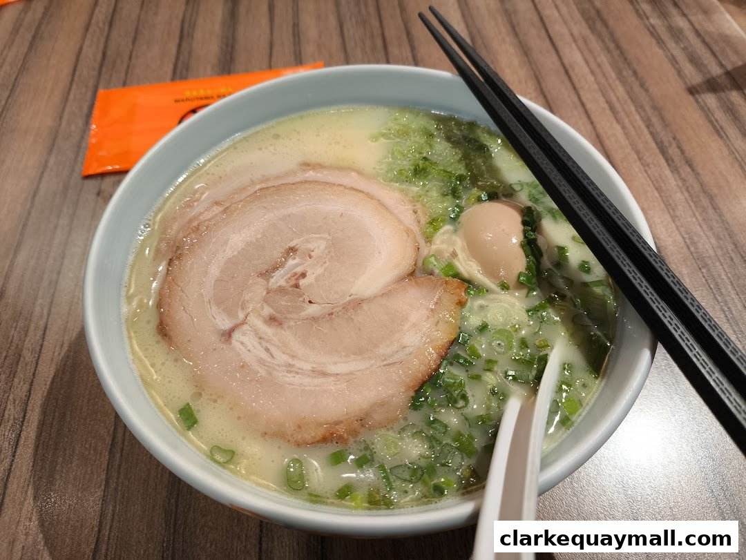 A steaming bowl of Tonkotsu ramen with chashu pork, egg, and green onions.