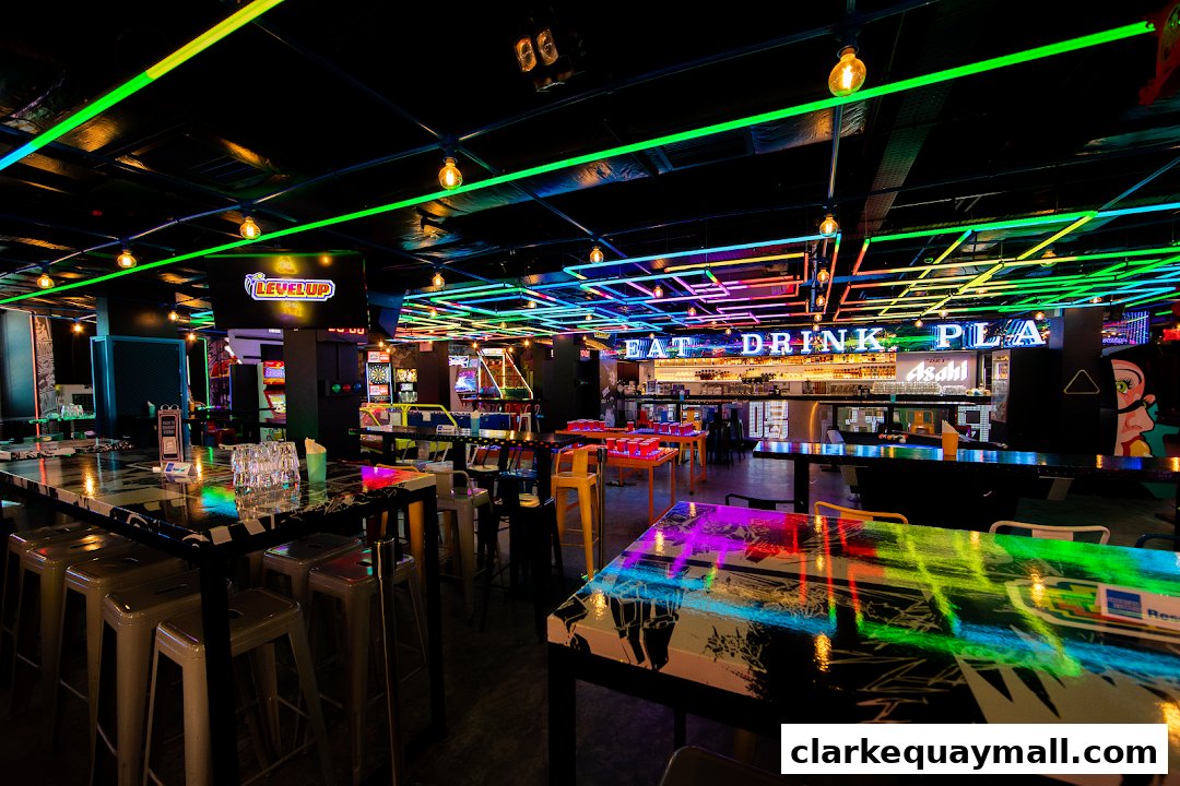 Interior of a vibrant arcade bar with neon lights, gaming machines, and seating areas.