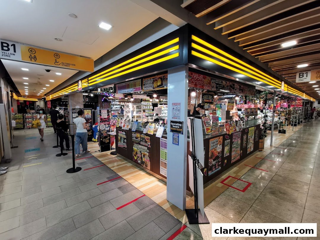 The exterior of a DON DON DONKI store in a mall, showcasing various products and a queue line.