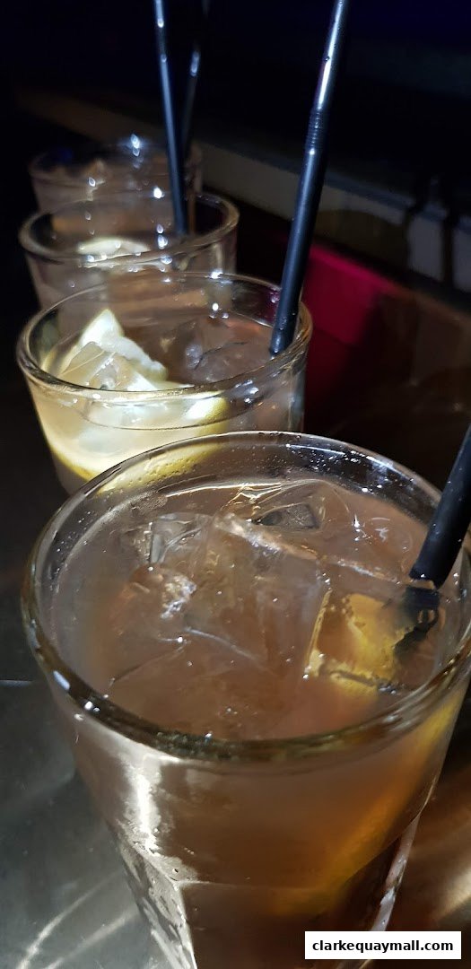 Close-up of iced drinks with lemon slices and straws in glasses.