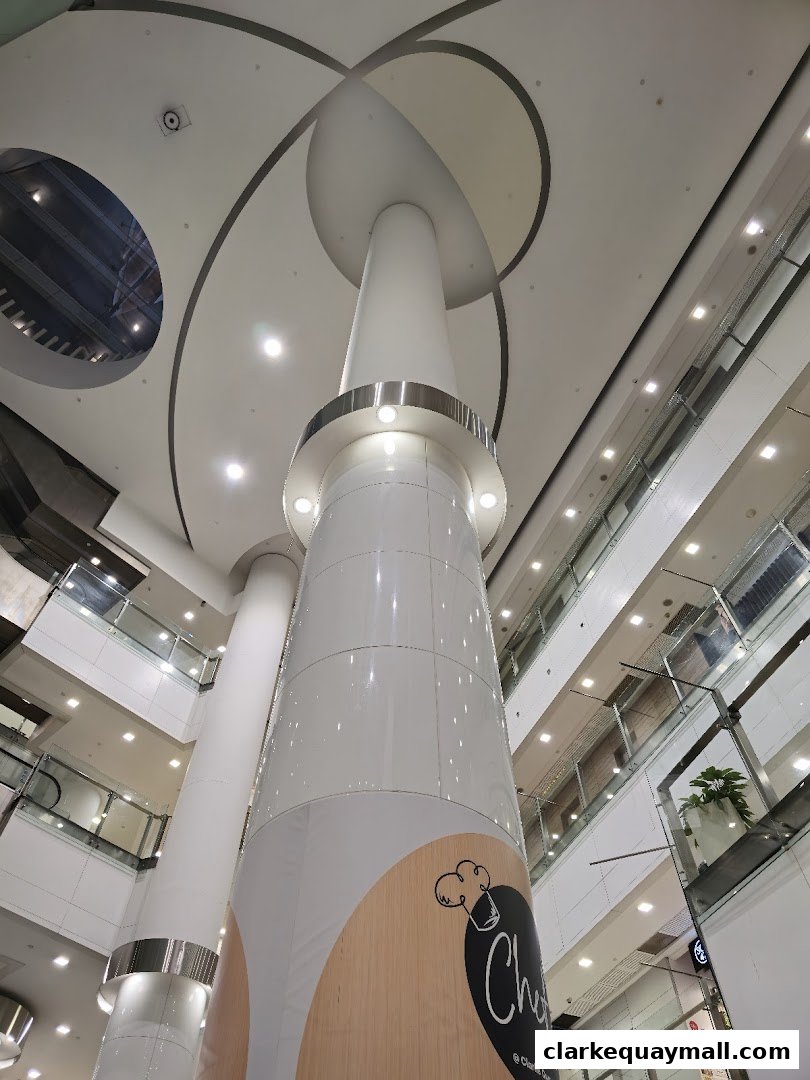 Interior view of a modern shopping mall with a large central pillar and multiple levels.