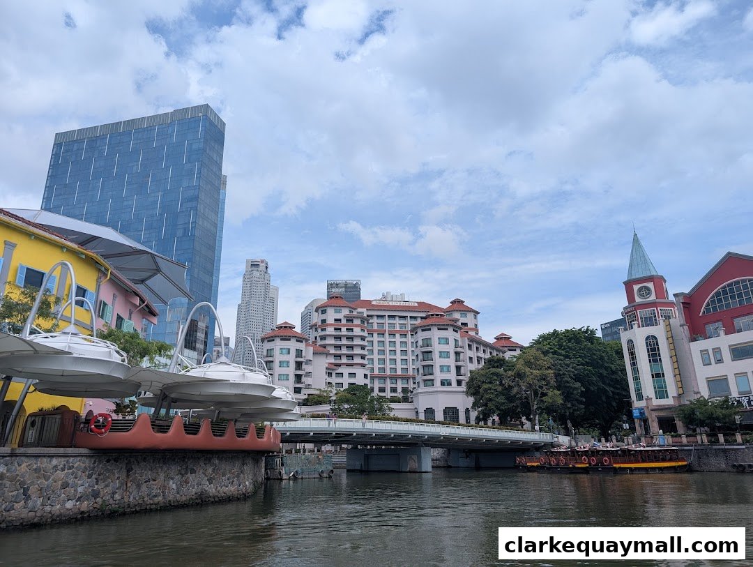 A scenic view of the Singapore River with boats and buildings under a cloudy sky.