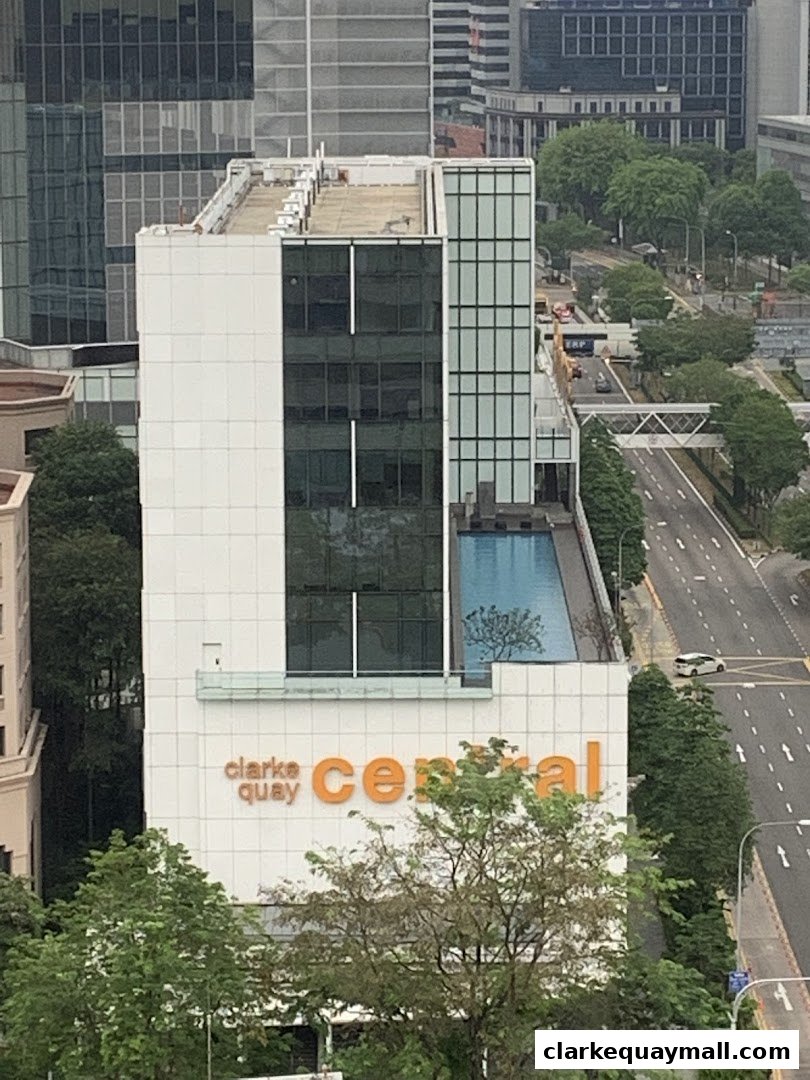 An aerial view of the Clarke Quay Central building with a rooftop pool and surrounding cityscape.
