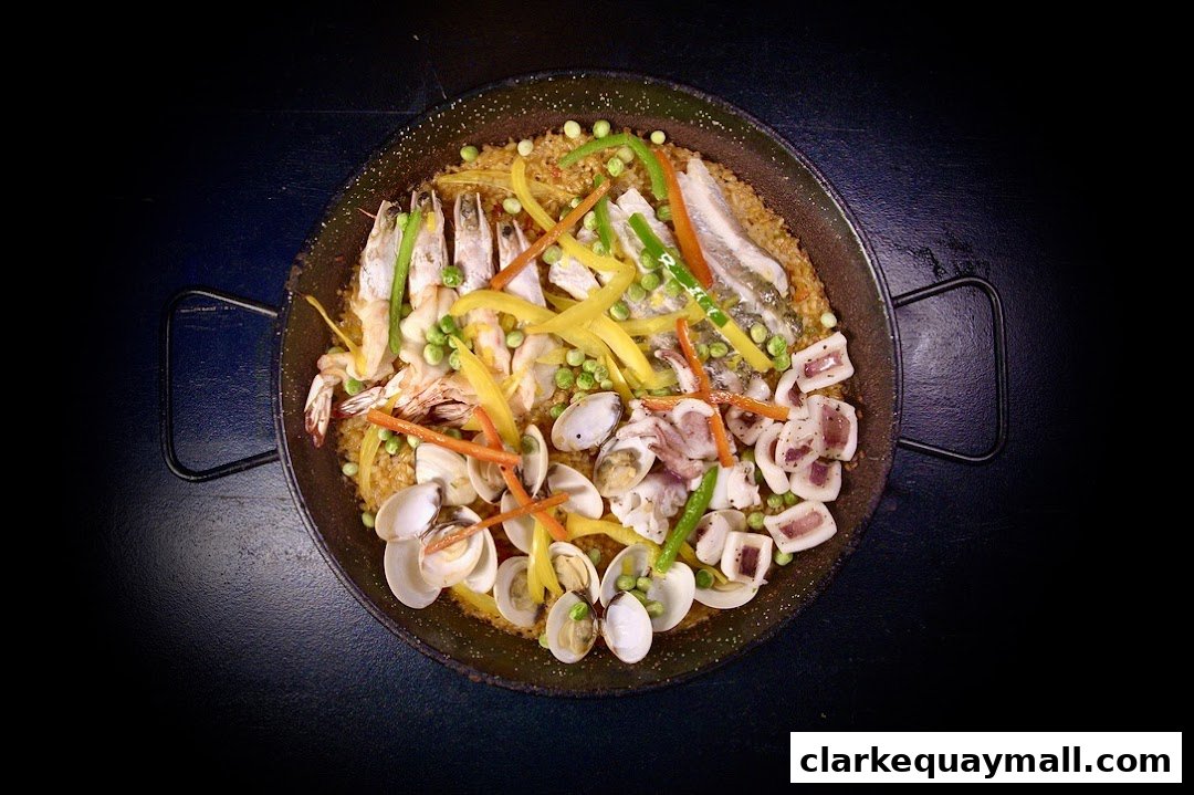A top-down view of a seafood paella dish with shrimp, clams, squid, and vegetables.