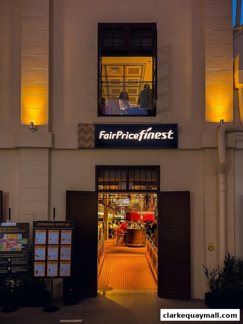 The illuminated entrance of FairPrice Finest Clarke Quay, showcasing an inviting interior and an opening specials board.