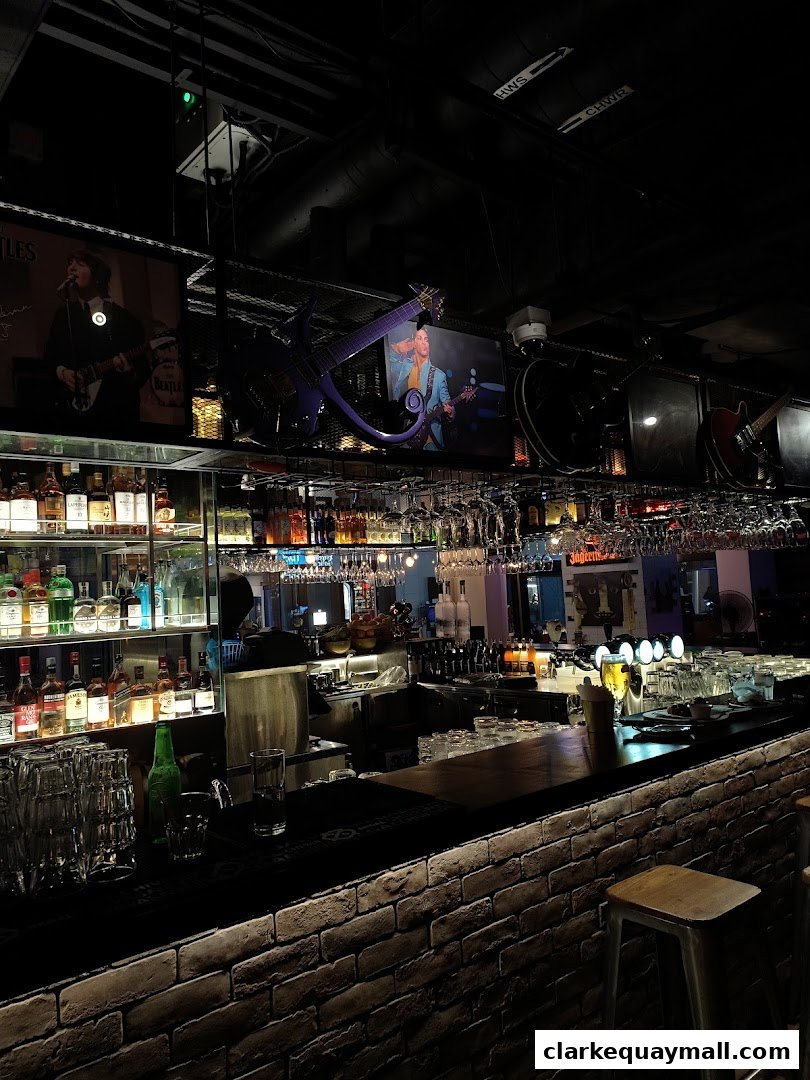 A dimly lit bar with a brick counter, stocked shelves, and rock memorabilia.