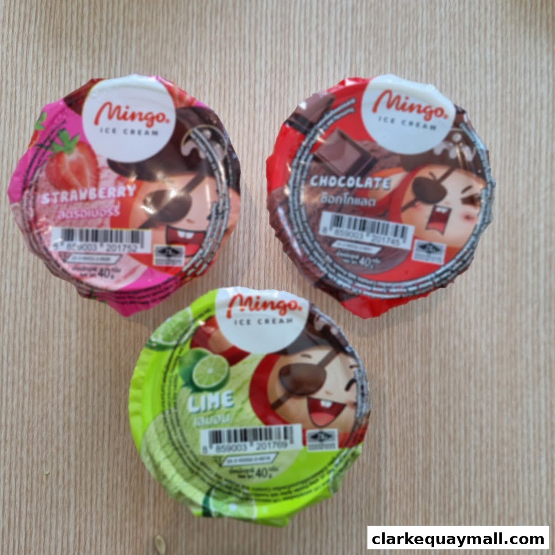 Three Mingo ice cream cups: strawberry, chocolate, and lime flavors, on a wooden surface.