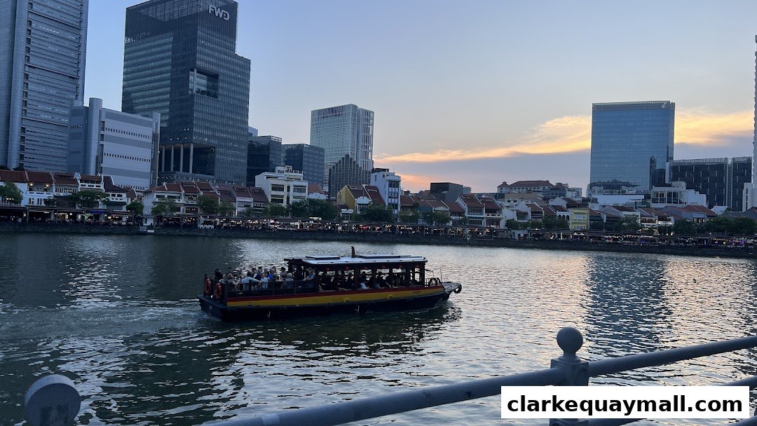 A river cruise boat with passengers sails past a waterfront cityscape at dusk.