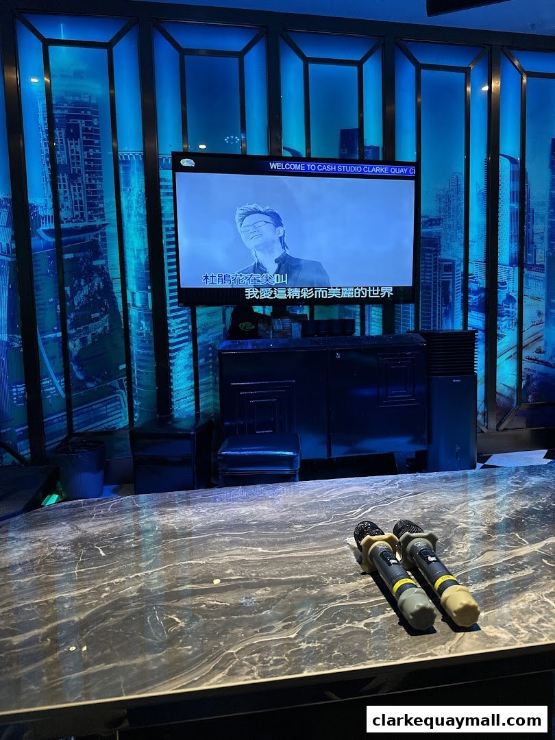 A karaoke room with a screen displaying lyrics and two microphones on a marble table.