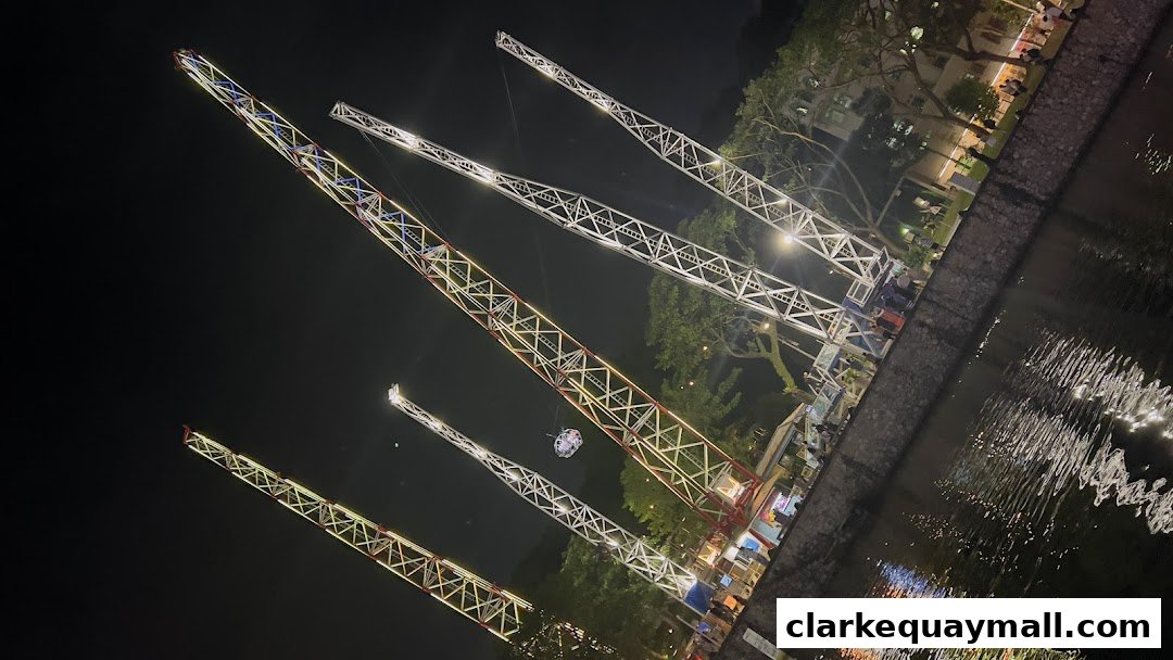 Night view of the Slingshot Singapore amusement ride with illuminated towers and a capsule in the air.