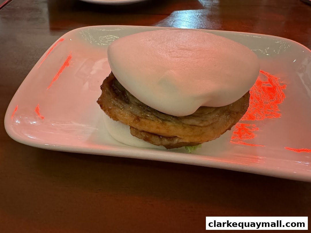 A close-up of a delicious pork belly bao bun served on a white plate.