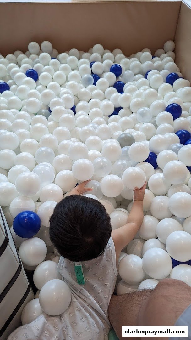 A child plays in a large ball pit filled with white and blue balls.