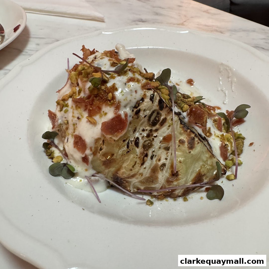 A beautifully plated dish featuring grilled cabbage with creamy sauce, pistachios, and crispy toppings.