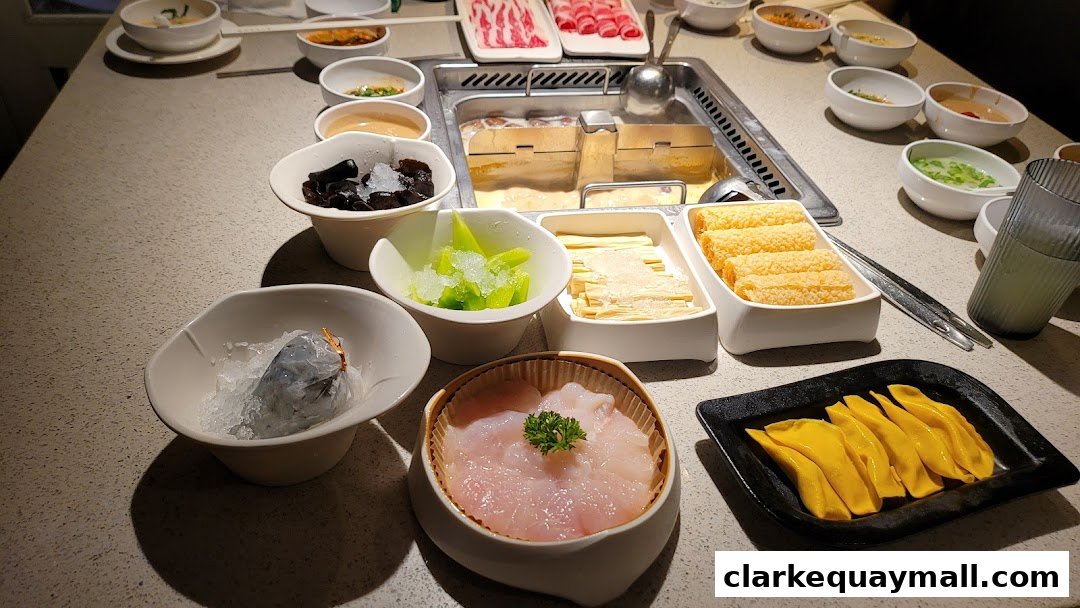 A table filled with various ingredients for hot pot, including meats, vegetables, and seafood.