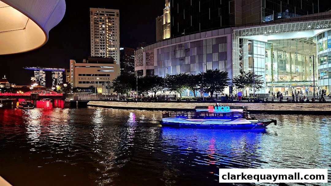 A scenic night view of a river with a boat, illuminated buildings, and people enjoying the waterfront.