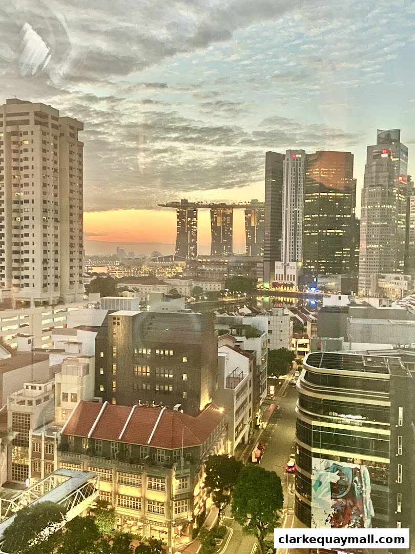 A panoramic cityscape view of Singapore at dusk, featuring iconic skyscrapers and buildings.