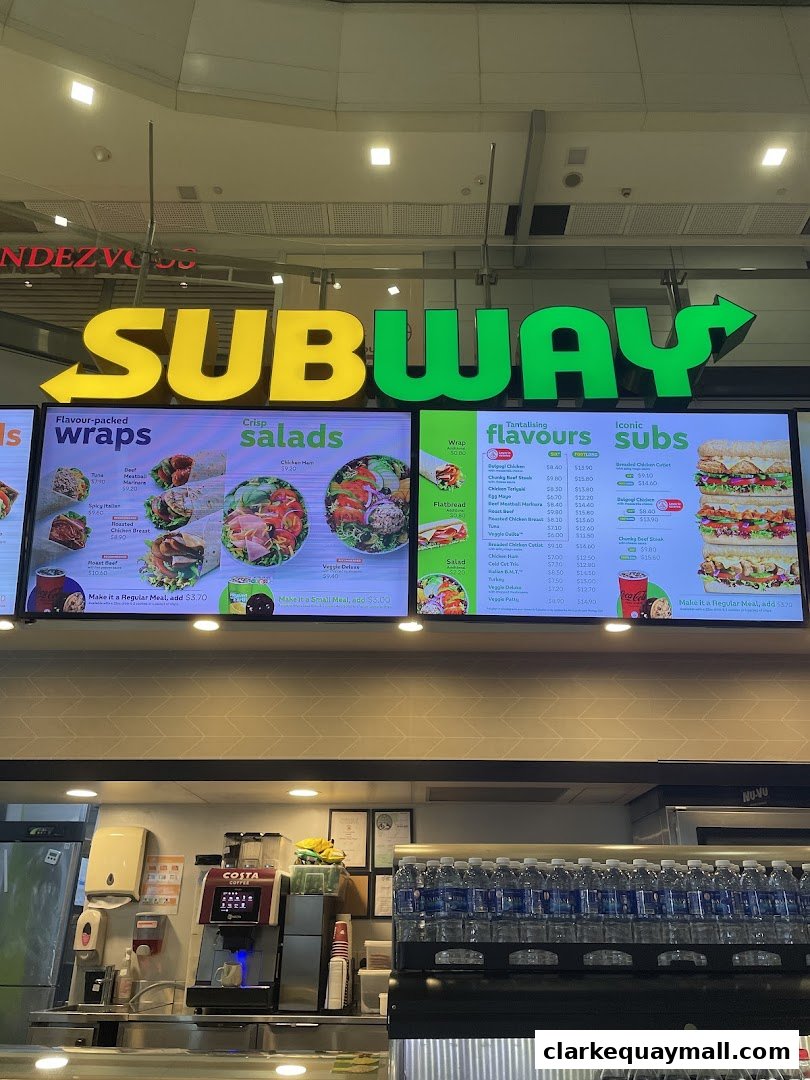 A Subway restaurant menu board displaying various wraps, salads, and subs with prices.