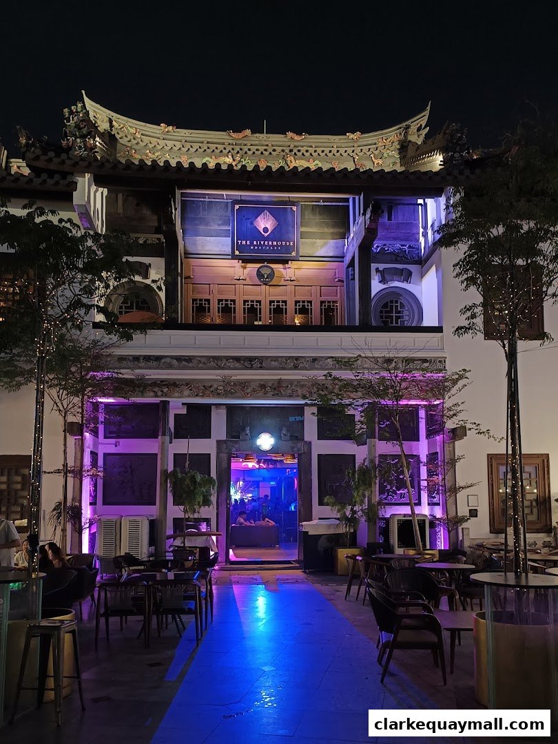 The Riverhouse bar entrance at night with purple and blue lighting and outdoor seating.