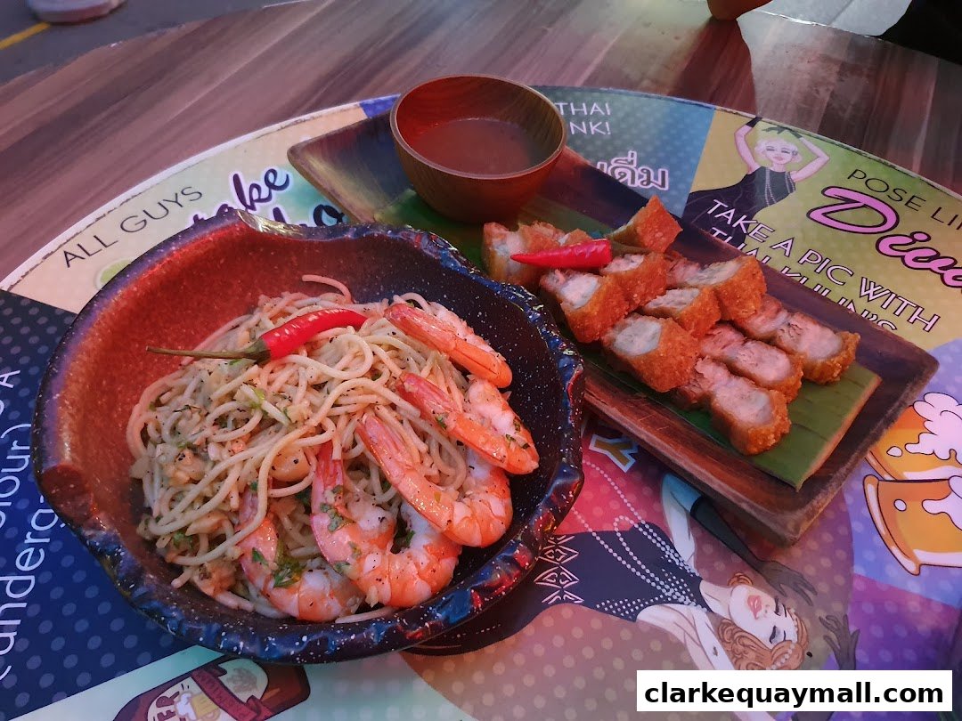 A close-up of a seafood pasta dish and crispy pork belly served at a bar.