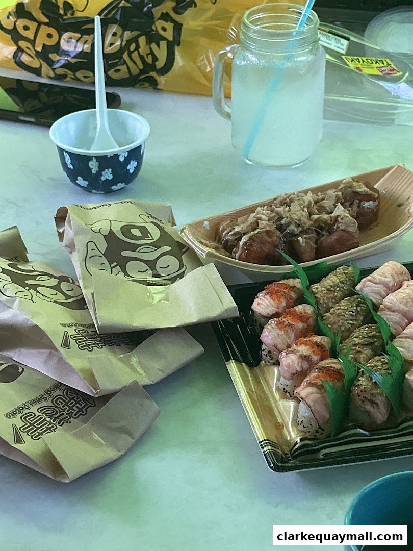 A table spread with Japanese food including sushi, takoyaki, and a drink.