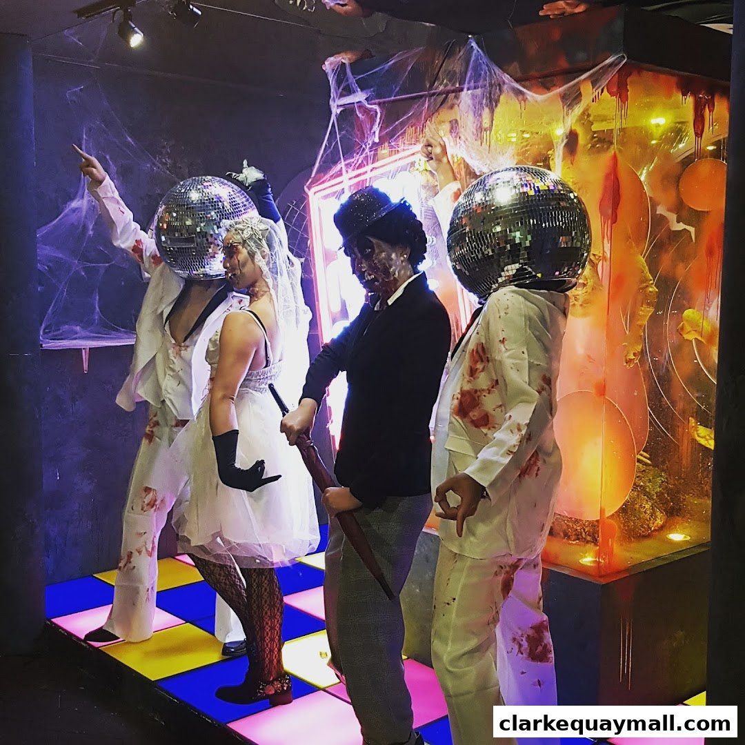 People in Halloween costumes with disco ball heads and bloody outfits pose on a colorful dance floor.