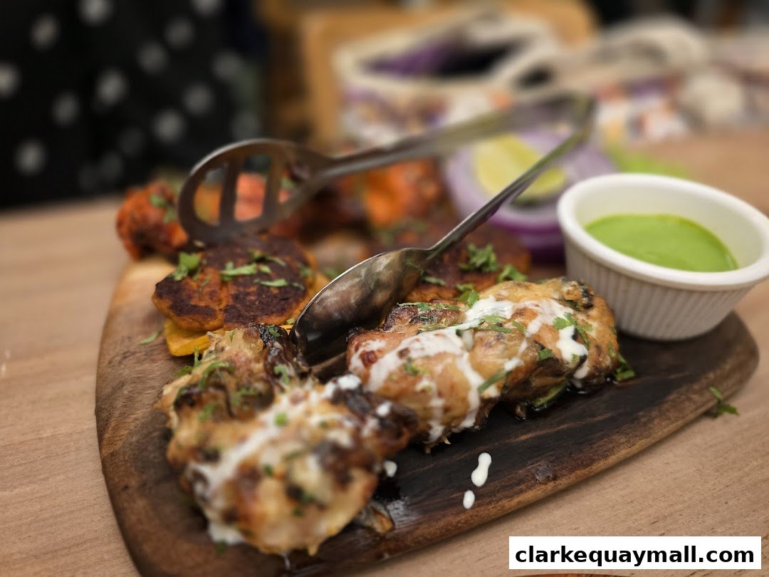 A wooden platter filled with various grilled meats and a side of green chutney.