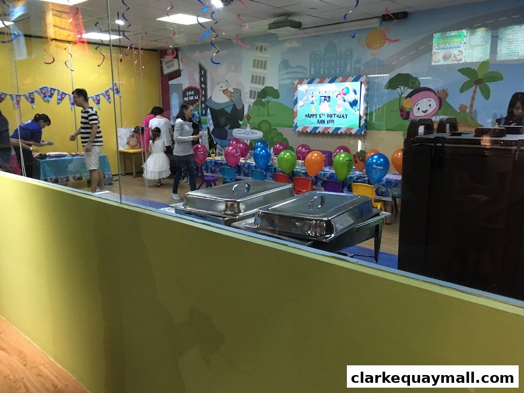 A birthday party setup with balloons, food warmers, and people celebrating.