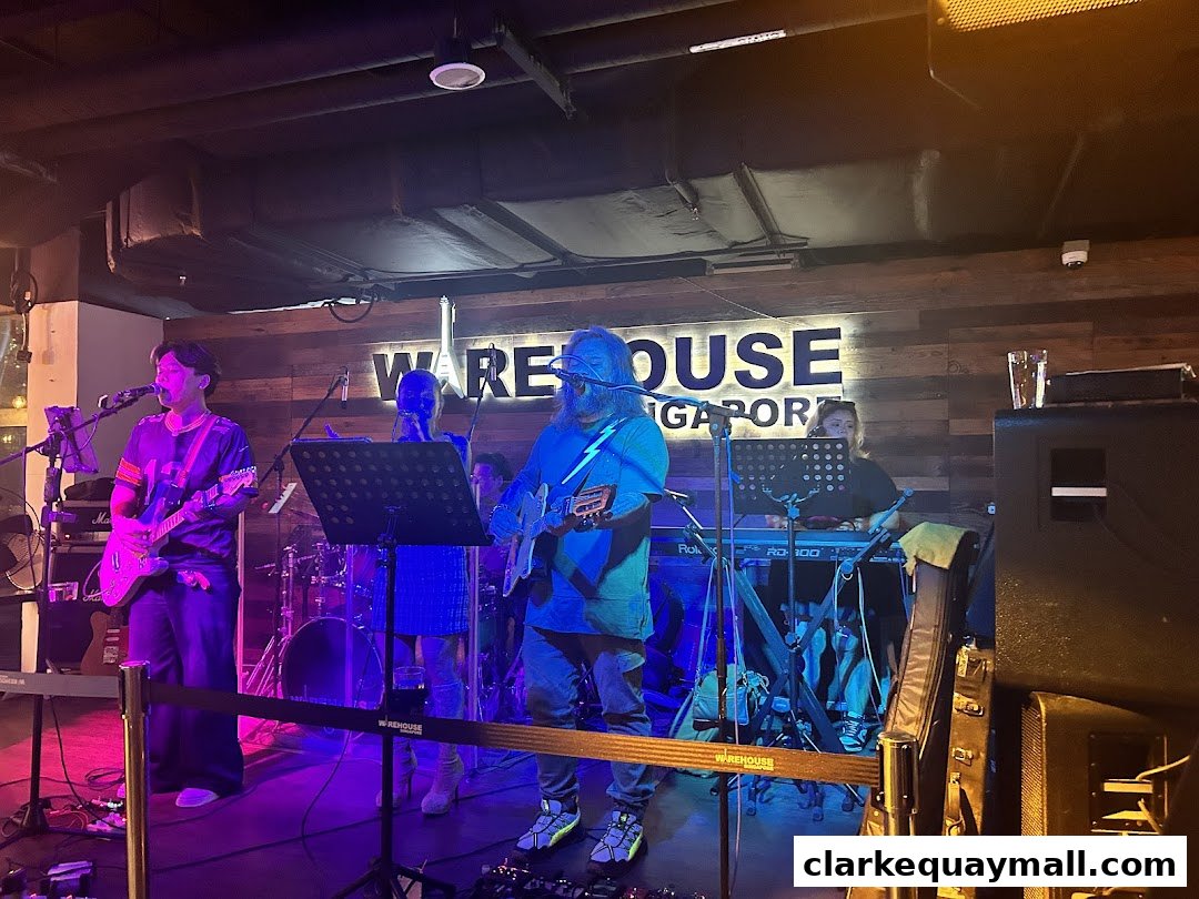 A live band performs on stage at Warehouse Bar, Singapore, under colorful lighting.