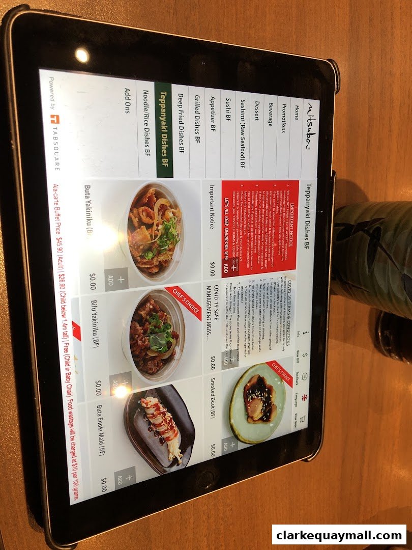 A tablet displays the menu for Mitsuba Japanese Restaurant, featuring various dishes and COVID-19 safety information.