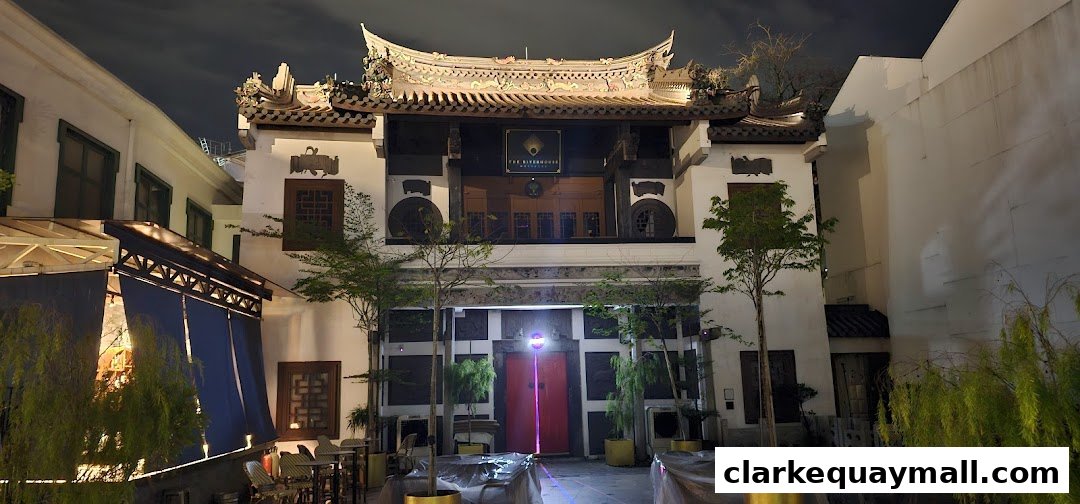 The exterior of a traditional building at night, with a red door and outdoor seating.