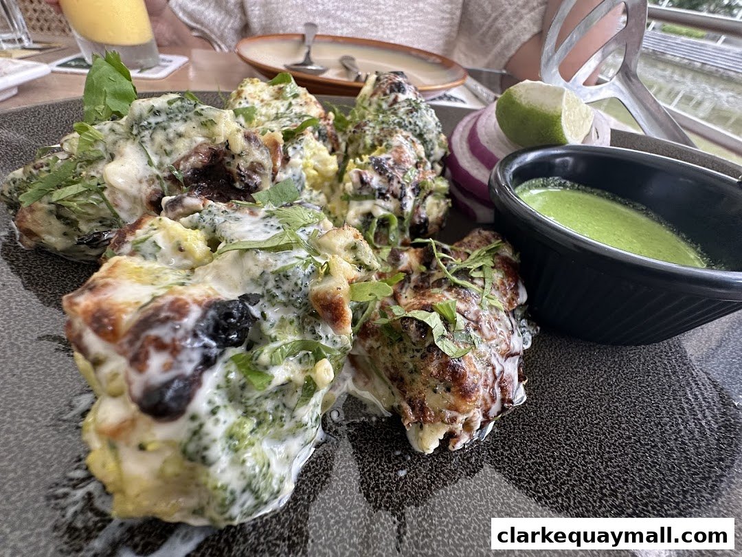 A close-up of a dish featuring broccoli florets coated in a creamy sauce, served with a side of green chutney.