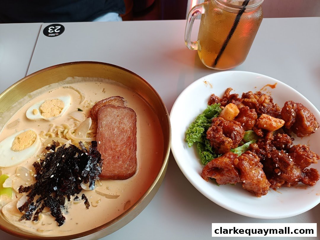 A close-up of Korean street food, featuring a creamy noodle soup and crispy fried chicken.
