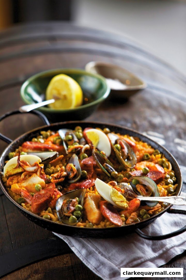 A close-up of a seafood paella dish with mussels, shrimp, chorizo, and peas.