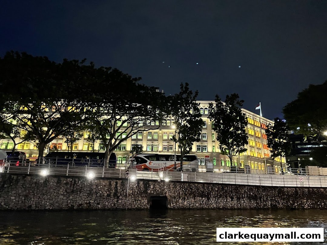 A brightly lit building with colorful windows at night, seen from across a river.