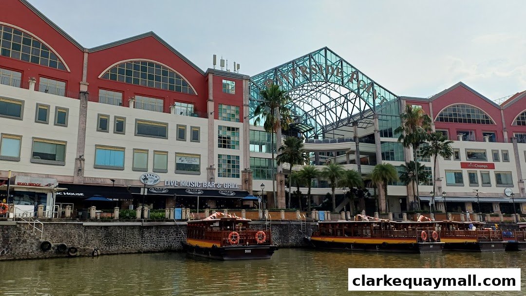 Boats docked by a waterfront building with shops and a glass-covered structure.
