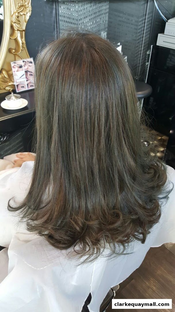 A person's back with freshly styled, wavy, ash-toned hair in a salon.