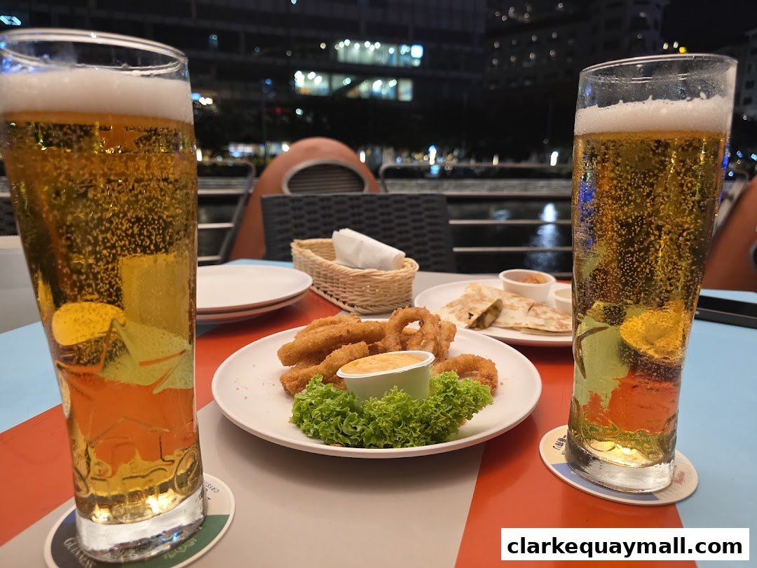 Two glasses of beer and appetizers on a table with a city view at night.