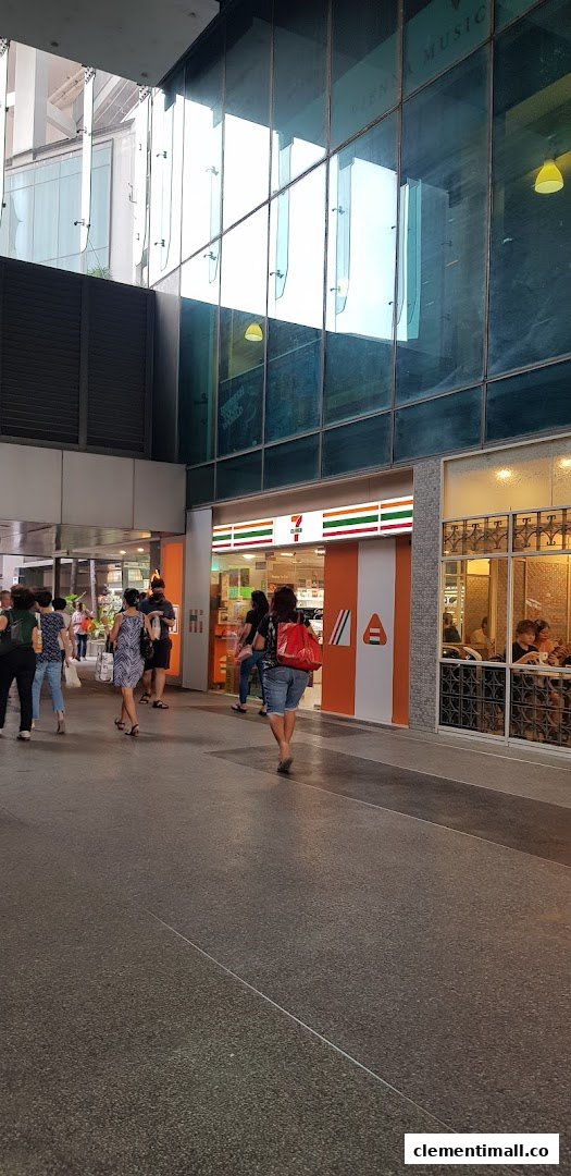 The exterior of a 7-Eleven convenience store with people walking past its entrance in an urban setting.