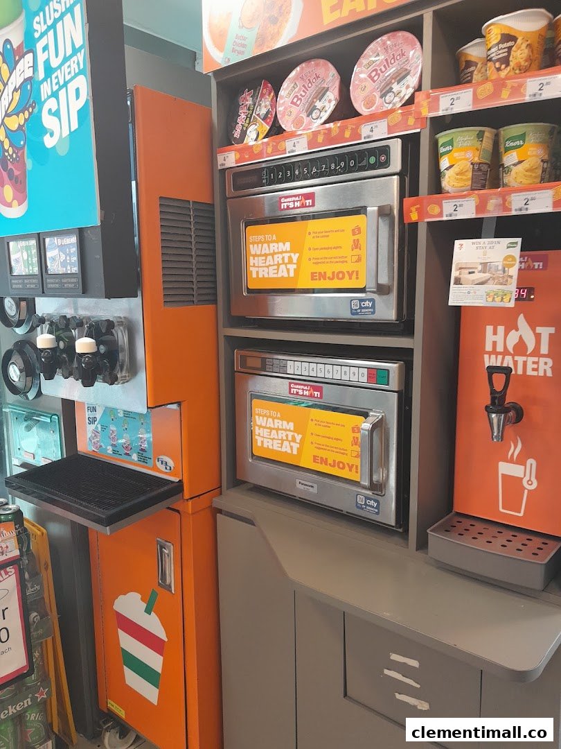 Interior view of a 7-Eleven convenience store featuring self-service Slurpee, microwave stations, and hot water dispenser.