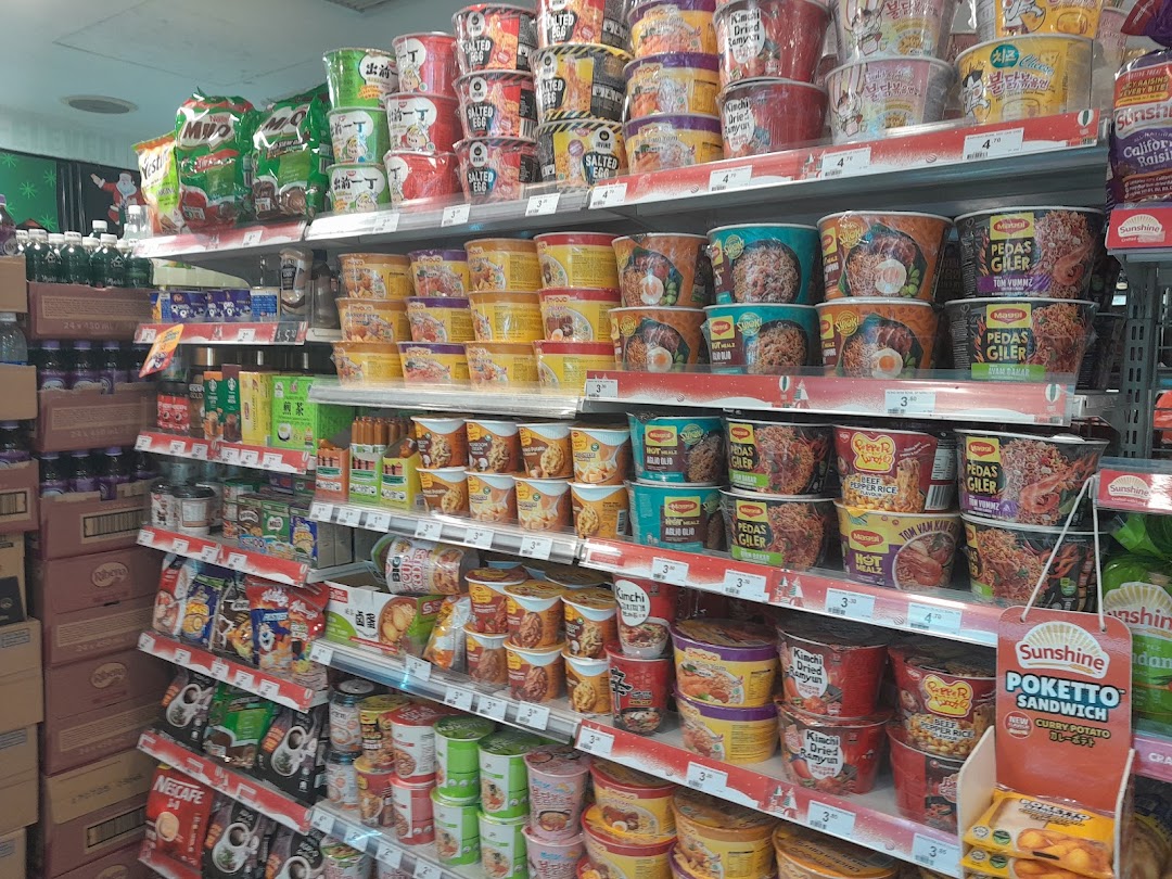 Shelves packed with instant noodles, beverages, and snacks in a well-stocked convenience store.